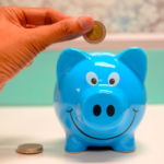 A person inserts coins into a piggy bank to save
