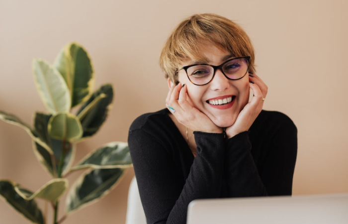 A young student smiles while taking classes online.