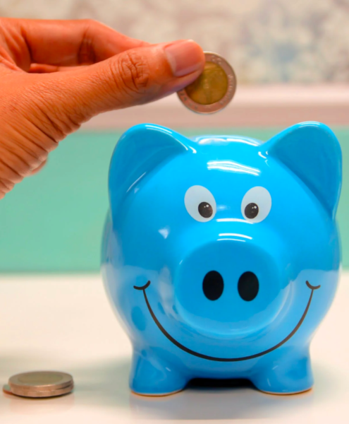 A person inserts coins into a piggy bank to save