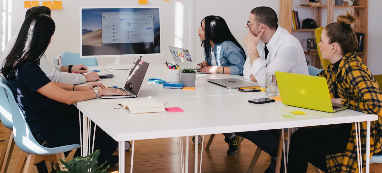 Employees in an office work around a table during a presentation.