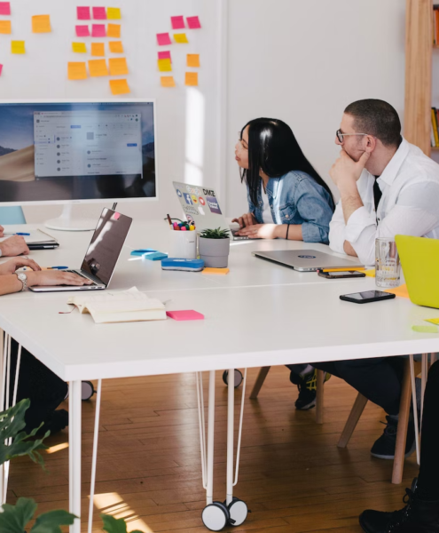 Employees in an office work around a table during a presentation.