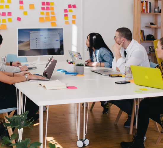 Employees in an office work around a table during a presentation.