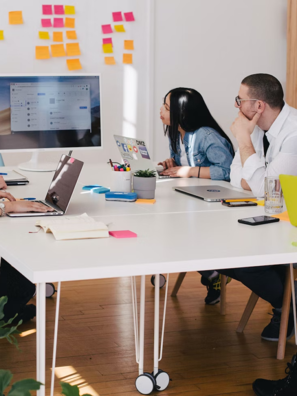 Employees in an office work around a table during a presentation.