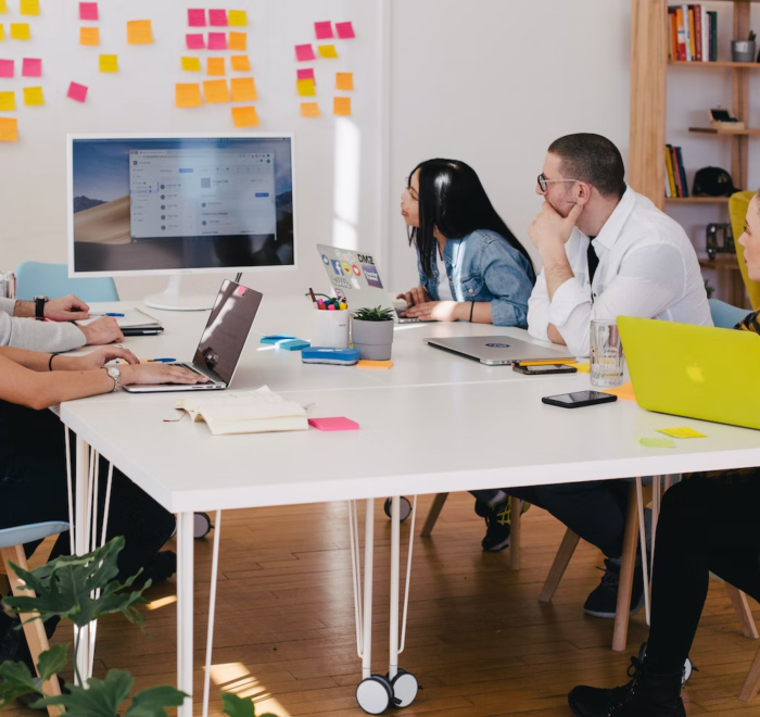 Employees in an office work around a table during a presentation.