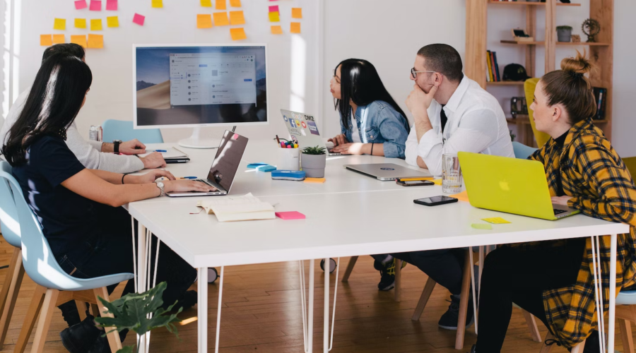 Employees in an office work around a table during a presentation.