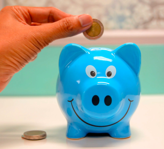 A person inserts coins into a piggy bank to save