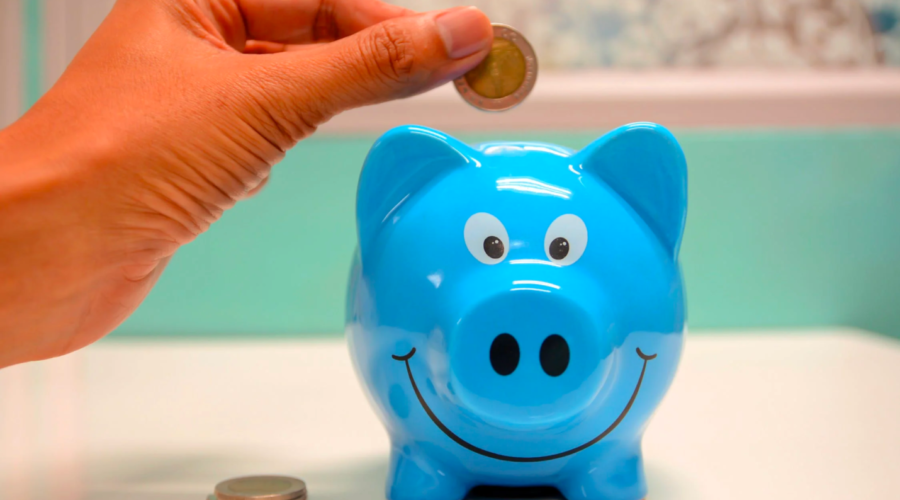 A person inserts coins into a piggy bank to save