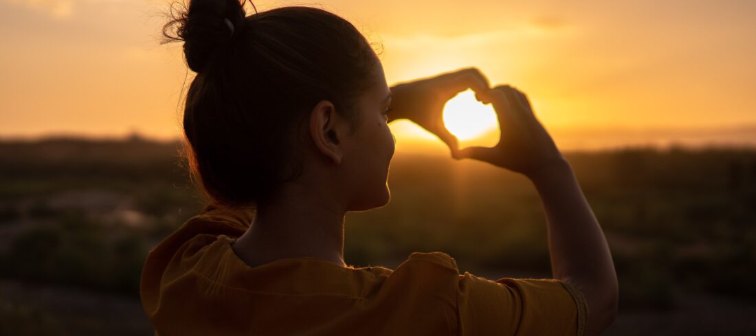 woman making a heart with her hands; getting through hard times