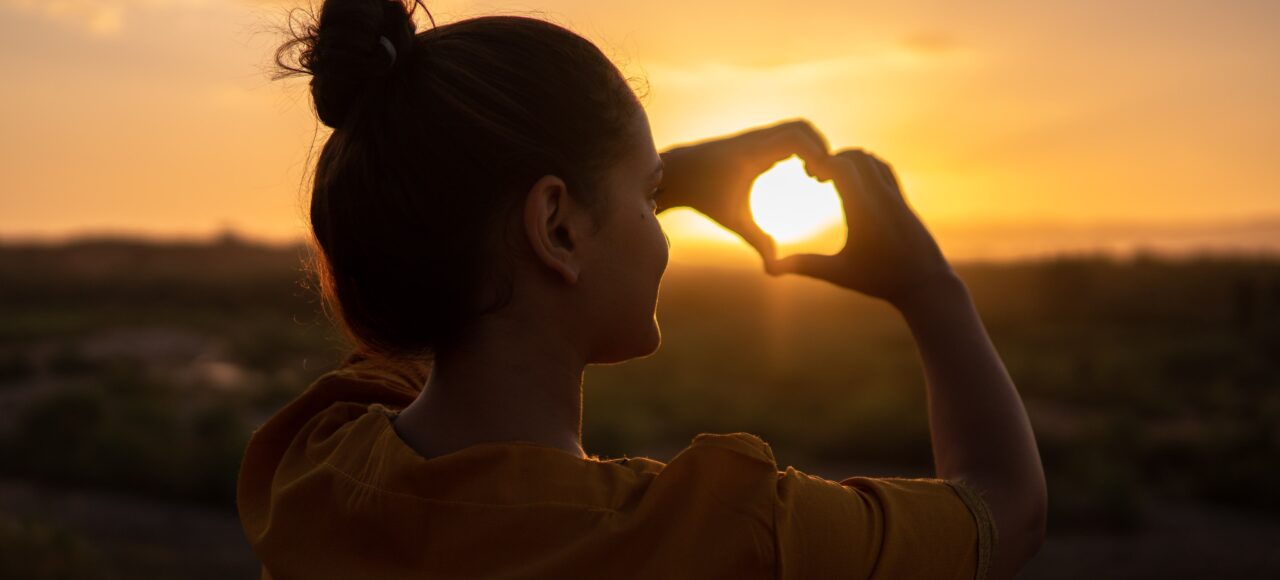 woman making a heart with her hands; getting through hard times