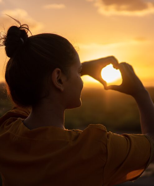 woman making a heart with her hands; getting through hard times