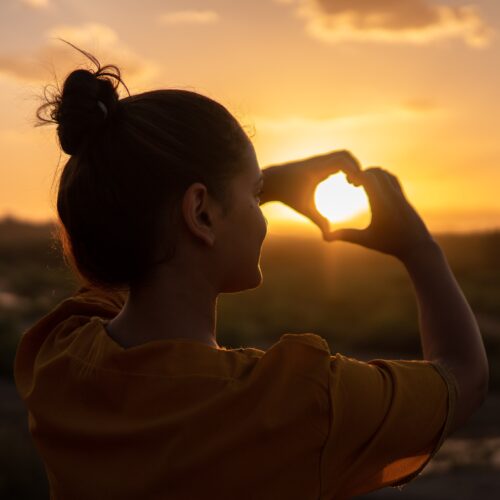 woman making a heart with her hands; getting through hard times