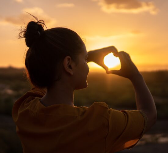 woman making a heart with her hands; getting through hard times