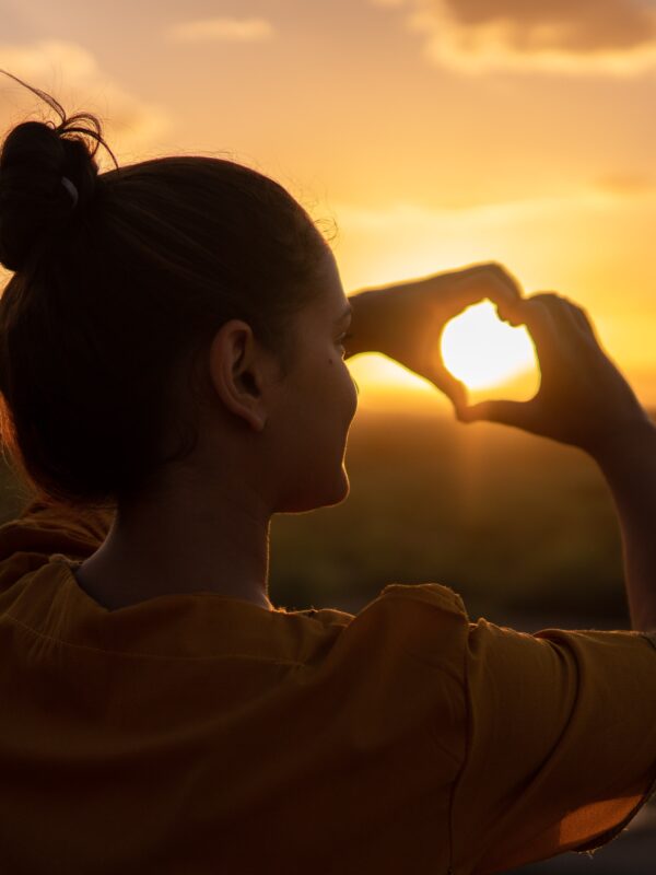 woman making a heart with her hands; getting through hard times