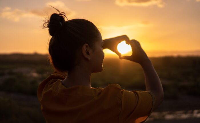 woman making a heart with her hands; getting through hard times