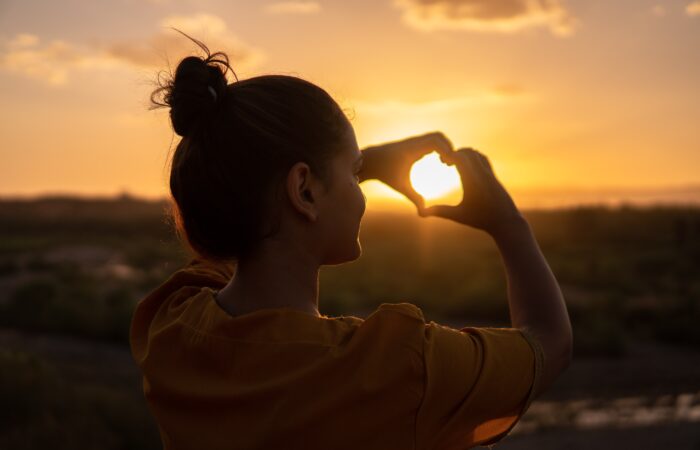 woman making a heart with her hands; getting through hard times