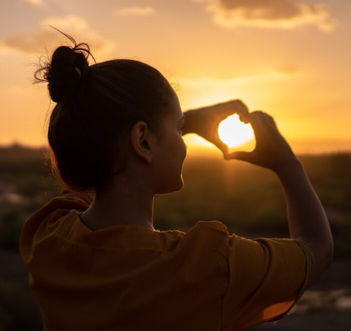 woman making a heart with her hands; getting through hard times