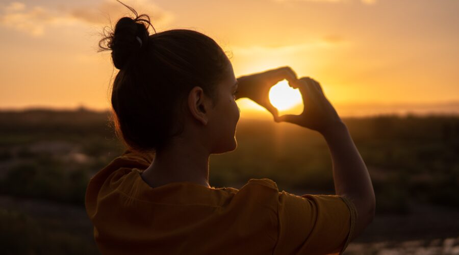 woman making a heart with her hands; getting through hard times