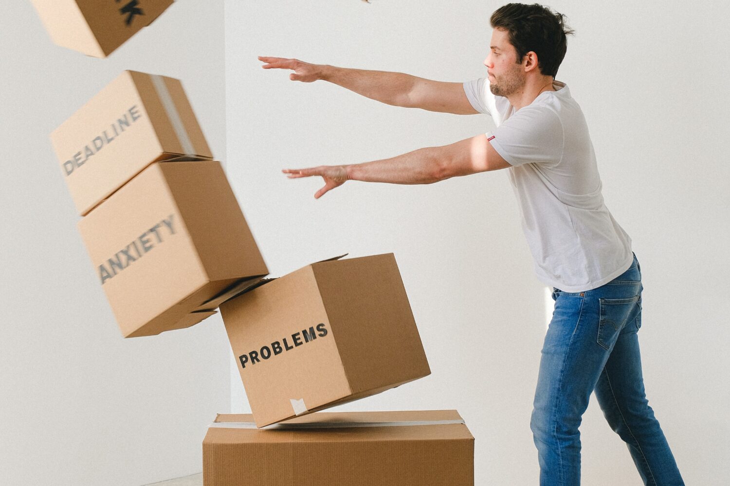 man pushing over boxes that represent all of his stresses