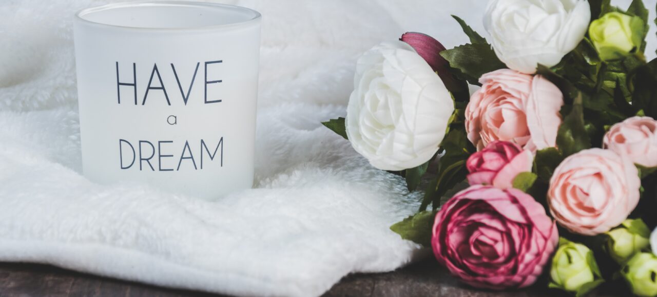 a mug that says "have a dream" next to a bouquet