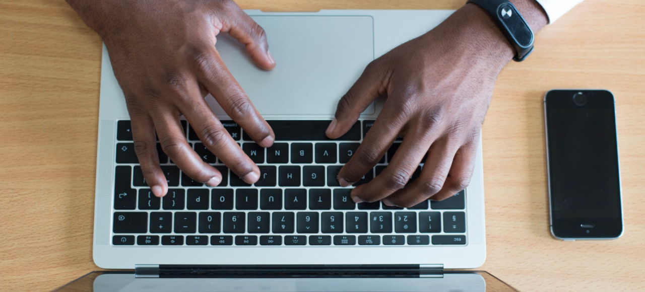 An IT professional works on his laptop while sitting at a desk.