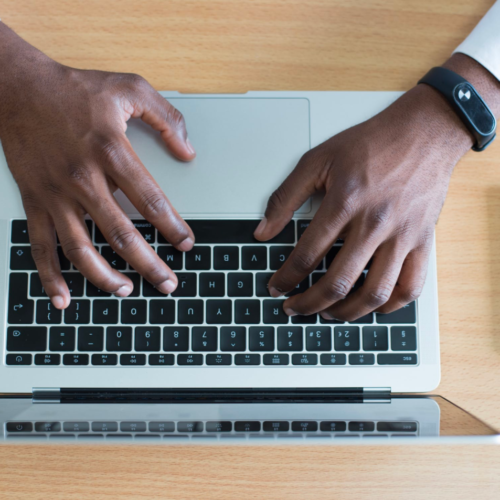 An IT professional works on his laptop while sitting at a desk.