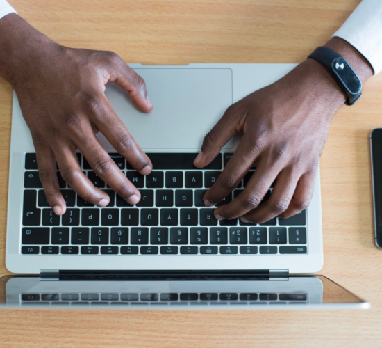 An IT professional works on his laptop while sitting at a desk.