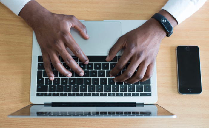 An IT professional works on his laptop while sitting at a desk.