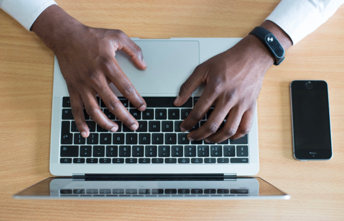 An IT professional works on his laptop while sitting at a desk.