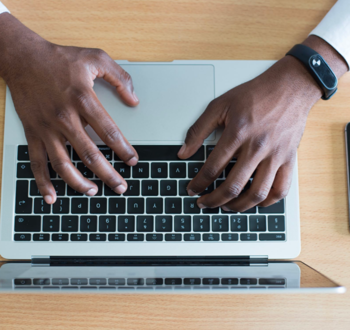 An IT professional works on his laptop while sitting at a desk.