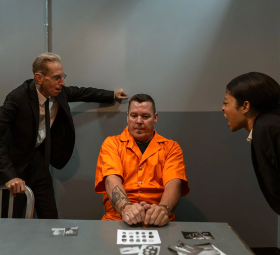 Two criminal justice professionals interrogate a prisoner aggressively
