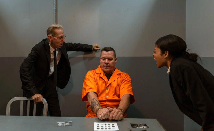 Two criminal justice professionals interrogate a prisoner aggressively