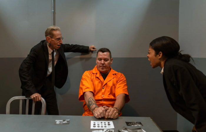 Two criminal justice professionals interrogate a prisoner aggressively