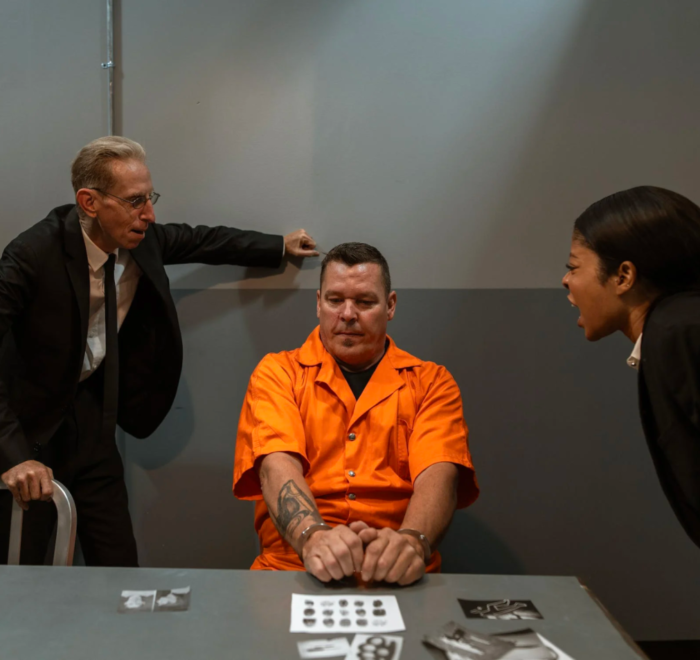 Two criminal justice professionals interrogate a prisoner aggressively