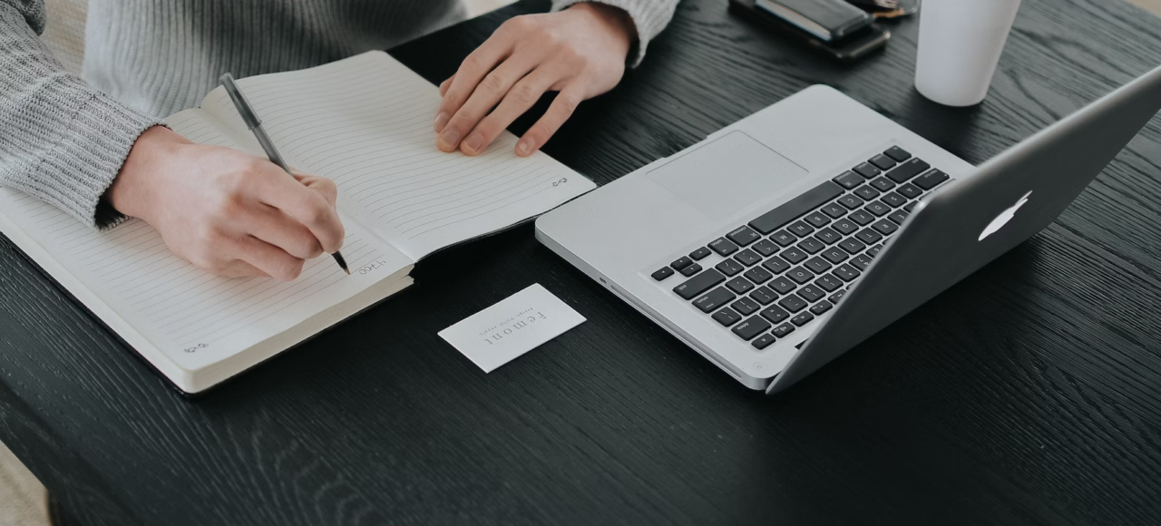 A person studies for an online degree while taking notes