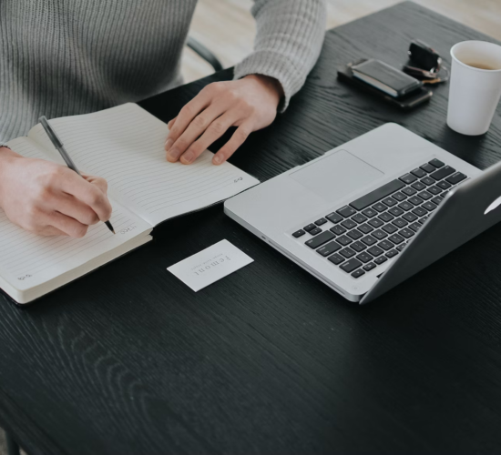 A person studies for an online degree while taking notes