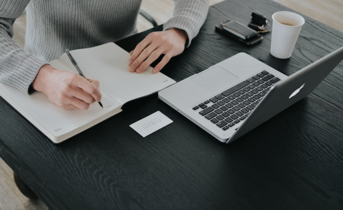 A person studies for an online degree while taking notes