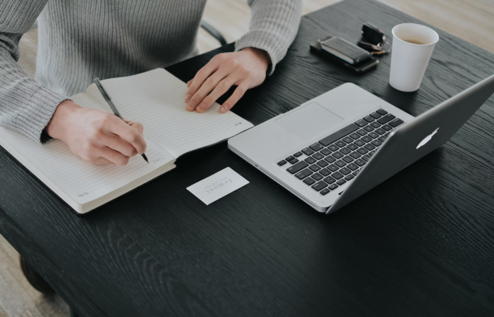 A person studies for an online degree while taking notes