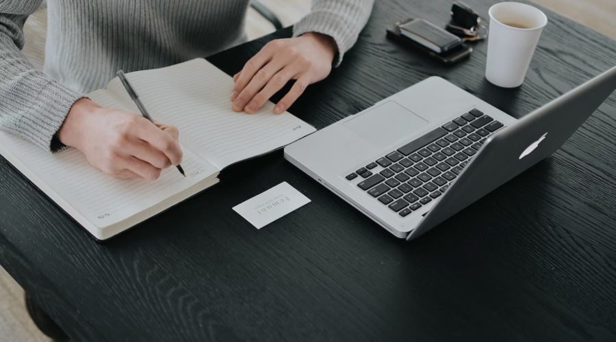 A person studies for an online degree while taking notes