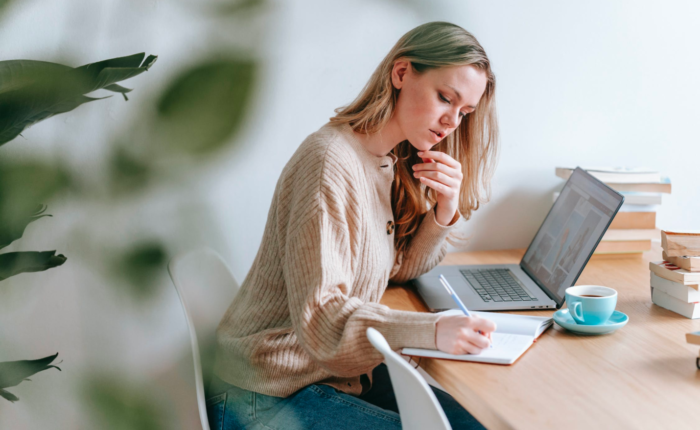 A grant writer works on her laptop and desk, taking notes