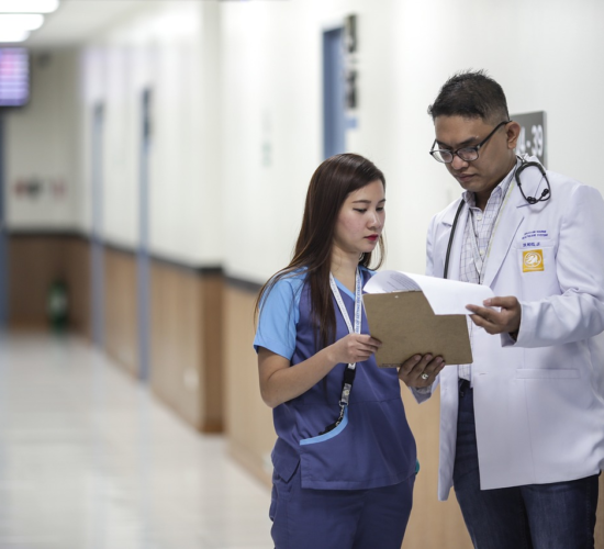 An administrative medical assistant talks to a doctor